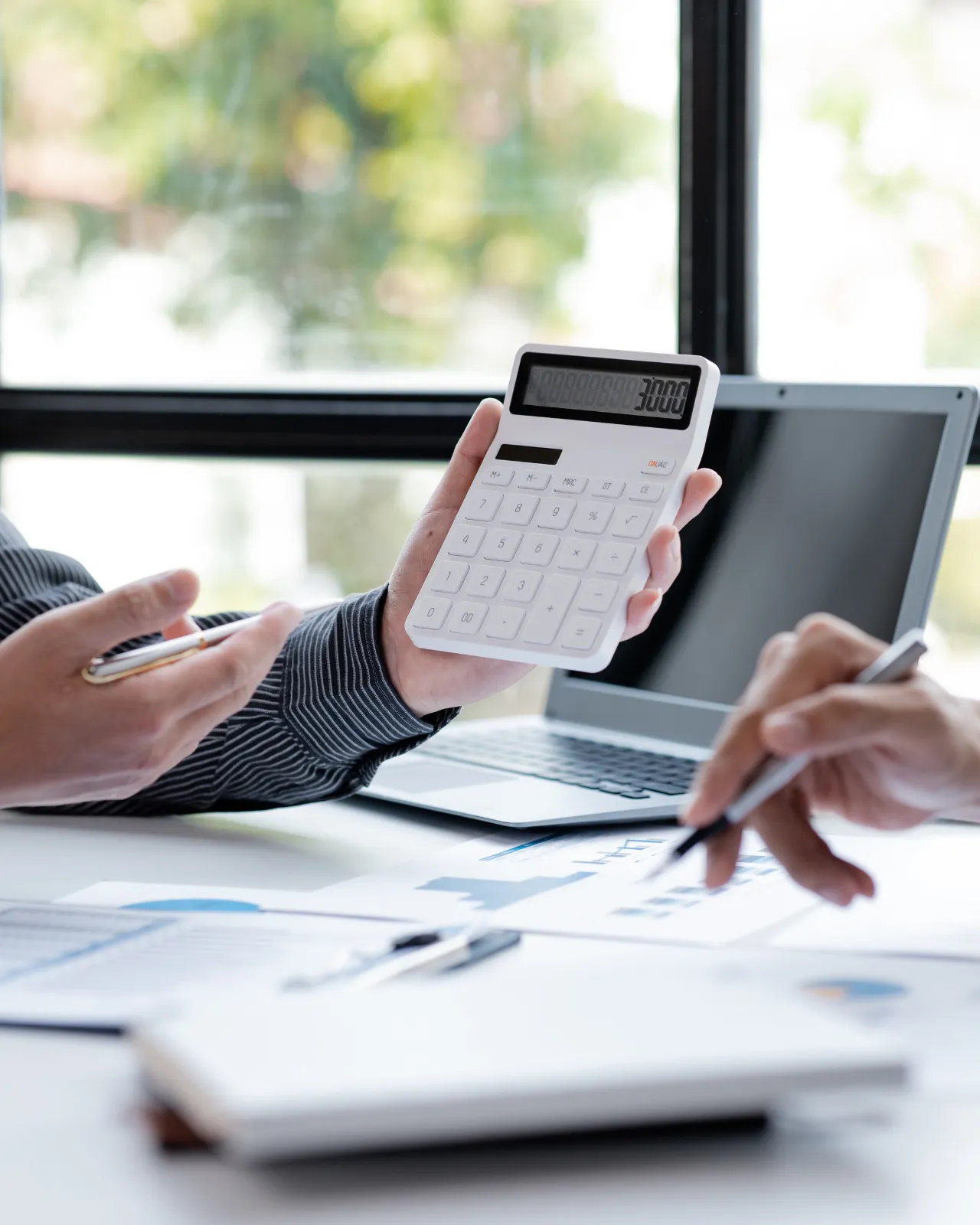 Asesor contable revisando facturas con calculadora y portátil